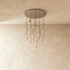 Clérachic chandelier with 21 clear glass teardrops on thin cords from a round satin nickel canopy, switched off, against limewashed plaster