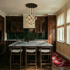 Clérachic chandelier with a round dark canopy and clear glass bulbs hanging above a marble kitchen island with three wooden stools