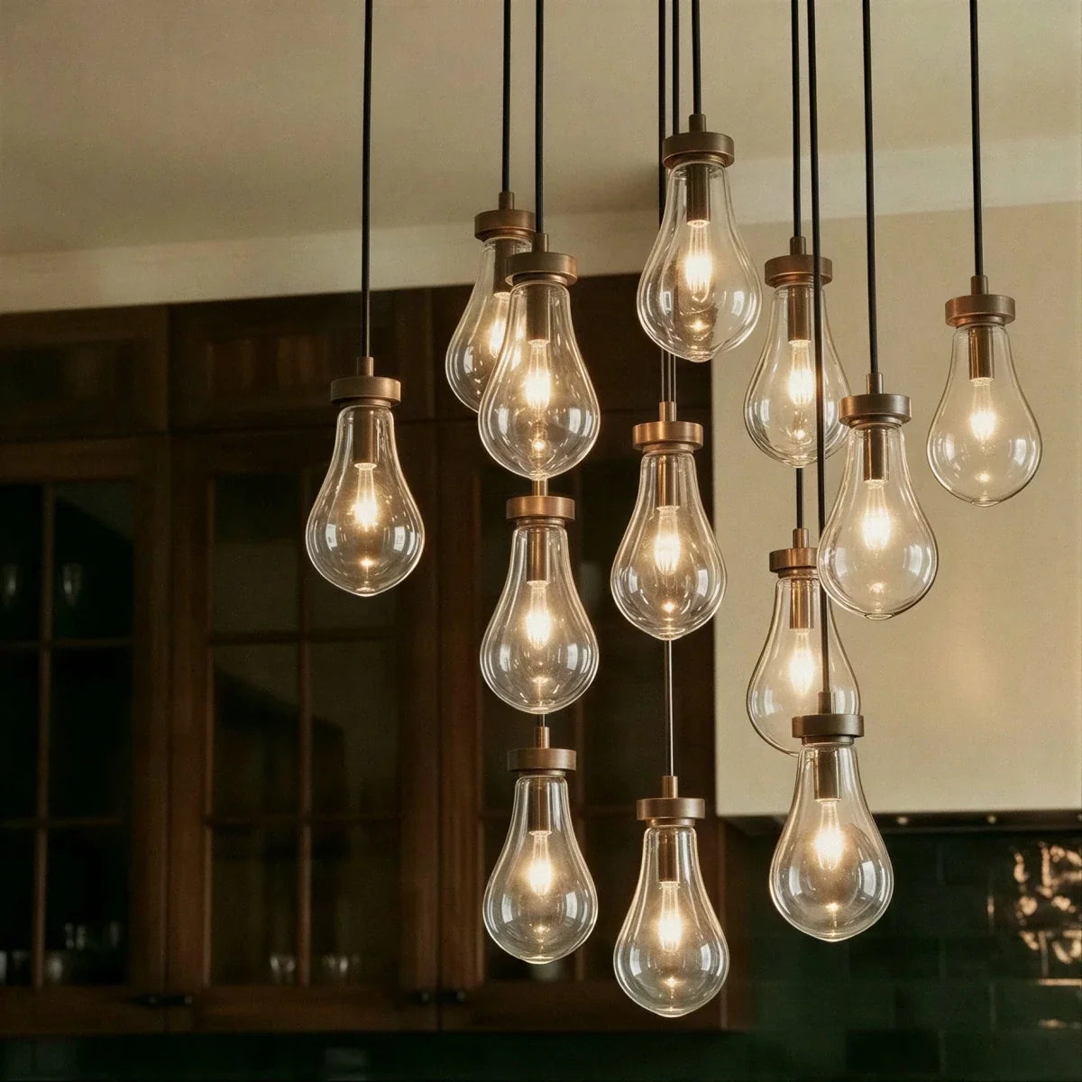 Close view of Clérachic chandelier bulbs in clear glass with bronze caps, glowing warm against dark wooden cabinets