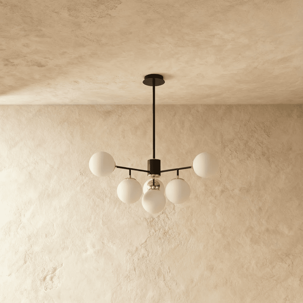 Clérachic black chandelier with 5 milky white glass globes on straight arms, unlit, against a limewash wall.