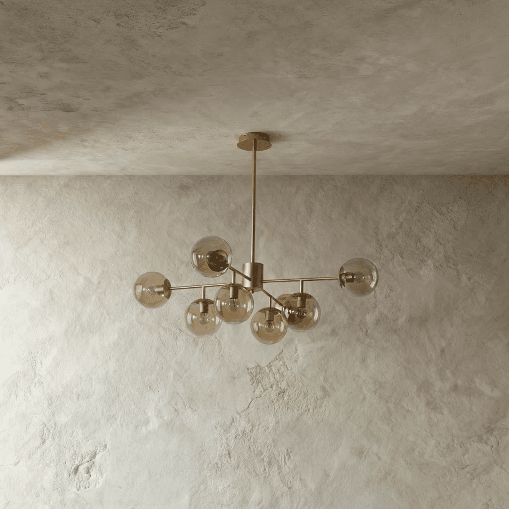 Clérachic gold chandelier with 7 cognac-tinted glass globes on straight arms, unlit, against a limewash wall.