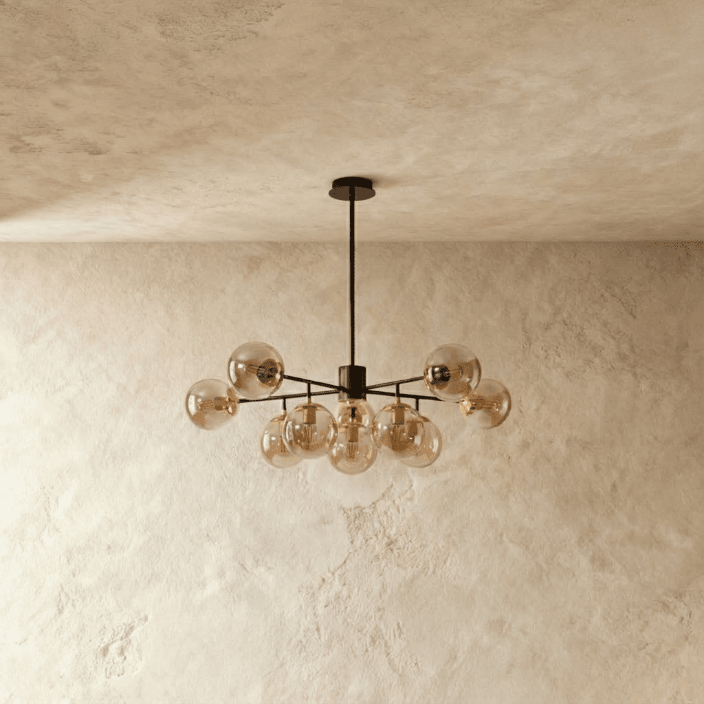 Clérachic black chandelier with 9 cognac-tinted glass globes on straight arms, unlit, against a limewash wall.