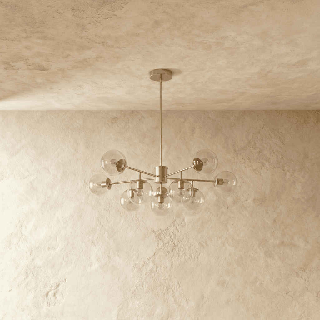 Clérachic silver chandelier with 9 clear glass globes on straight arms, unlit, against a limewash wall.