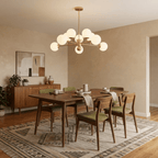 Clérachic gold chandelier with 9 milky white glass globes above a walnut dining table, in soft daylight, in a warm room.
