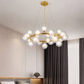 Clérachic gold ring chandelier of clear glass globes with frosted inner bulbs, hung on fine cables in a calm, neutral bedroom.