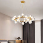 Clérachic gold ring chandelier of clear glass globes with frosted inner bulbs, hung on fine cables in a calm, neutral bedroom.