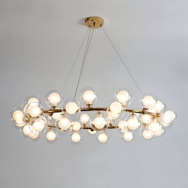 Clérachic large gold ring chandelier packed with clear glass globes and frosted bulbs, hung on cables from a round gold ceiling plate.
