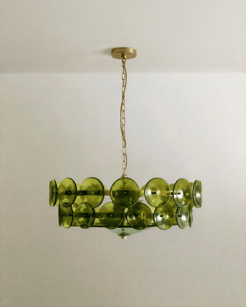 Clérachic two-tier chandelier with olive-green glass discs on a brass frame, hung on a fine brass chain against a pale ceiling.