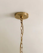 Clérachic brass ceiling canopy and a fine oval-link brass chain, shown close-up against a smooth pale ceiling.