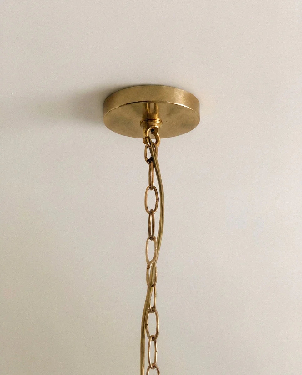 Clérachic brass ceiling canopy and a fine oval-link brass chain, shown close-up against a smooth pale ceiling.