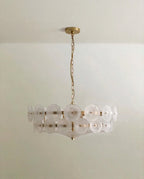 Clérachic chandelier with frosted, milky glass discs in two tiers on a brushed brass frame and chain, on a pale ceiling.