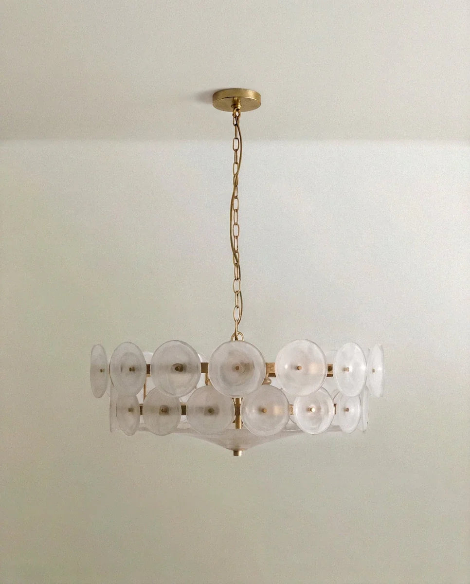Clérachic chandelier with frosted, milky glass discs in two tiers on a brushed brass frame and chain, on a pale ceiling.