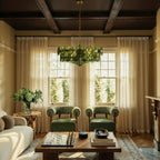 Clérachic chandelier with green glass discs and brass chain under dark beams, above a coffee table between two green armchairs.