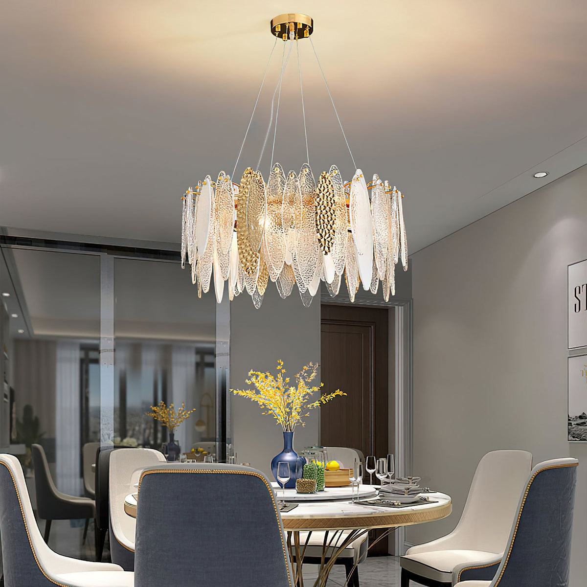 Over a round dining table, a Clérachic chandelier of clear and gold-toned glass leaves hangs from a brass canopy.