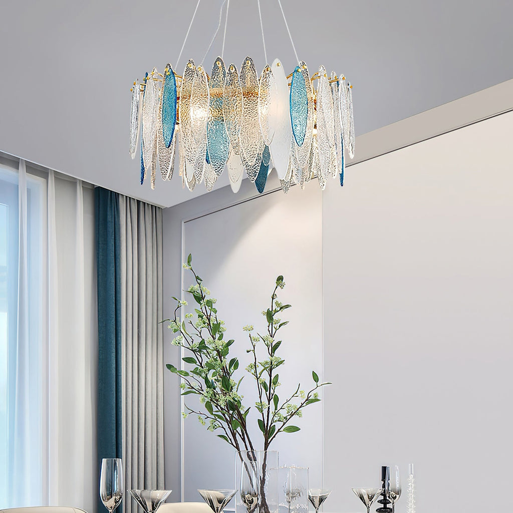 Clérachic chandelier with clear and blue glass leaves in a bright room, a leafy branch in a vase below.