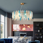 Clérachic glass chandelier with blue and clear leaf panels above an open kitchen with a marble island.