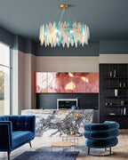 Tall view of a Clérachic blue and clear glass chandelier over a lounge with navy velvet chairs.