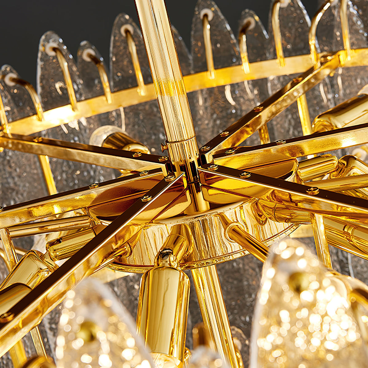 Close view of the gold frame, spokes and candle-style fittings inside this Clérachic glass chandelier.