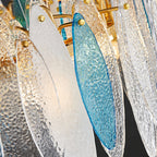 Close view of textured clear and blue glass leaves pinned to the gold ring of this Clérachic chandelier.