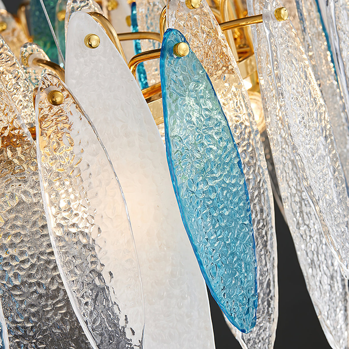 Close view of textured clear and blue glass leaves pinned to the gold ring of this Clérachic chandelier.