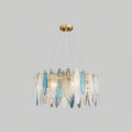 Smaller Clérachic chandelier in gold with clear and blue glass leaves, hanging on a light grey backdrop.