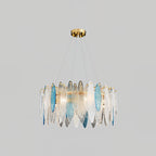 Smaller Clérachic chandelier in gold with clear and blue glass leaves, hanging on a light grey backdrop.