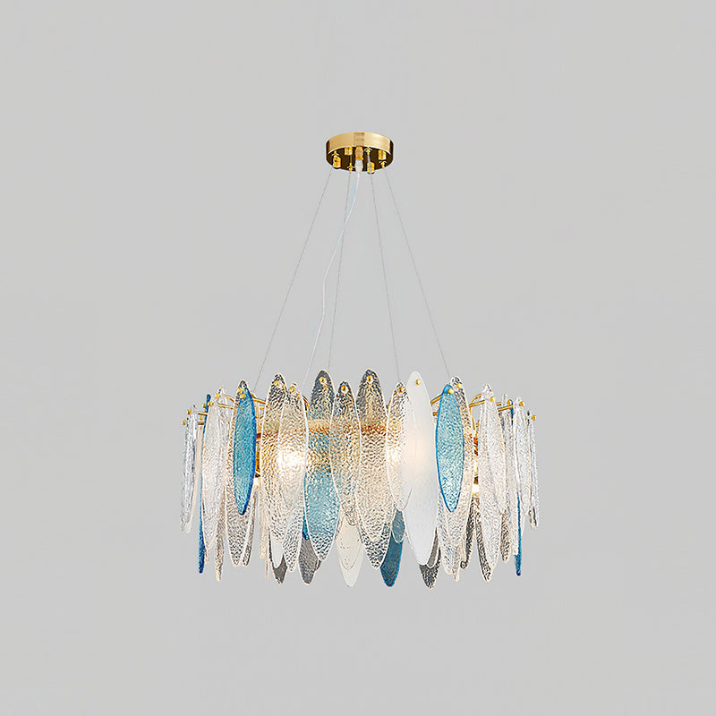 Smaller Clérachic chandelier in gold with clear and blue glass leaves, hanging on a light grey backdrop.