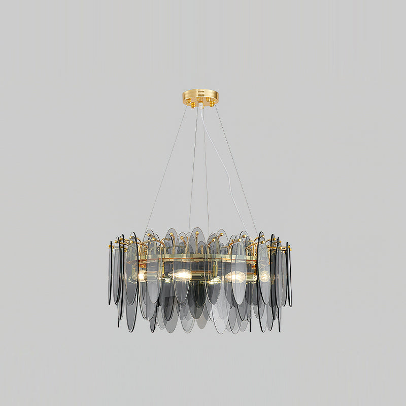 Clérachic chandelier in gold with smoke grey glass leaves, hanging against a light grey backdrop.