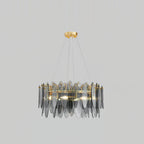 Clérachic chandelier in gold with smoke grey glass leaves, hanging against a light grey backdrop.
