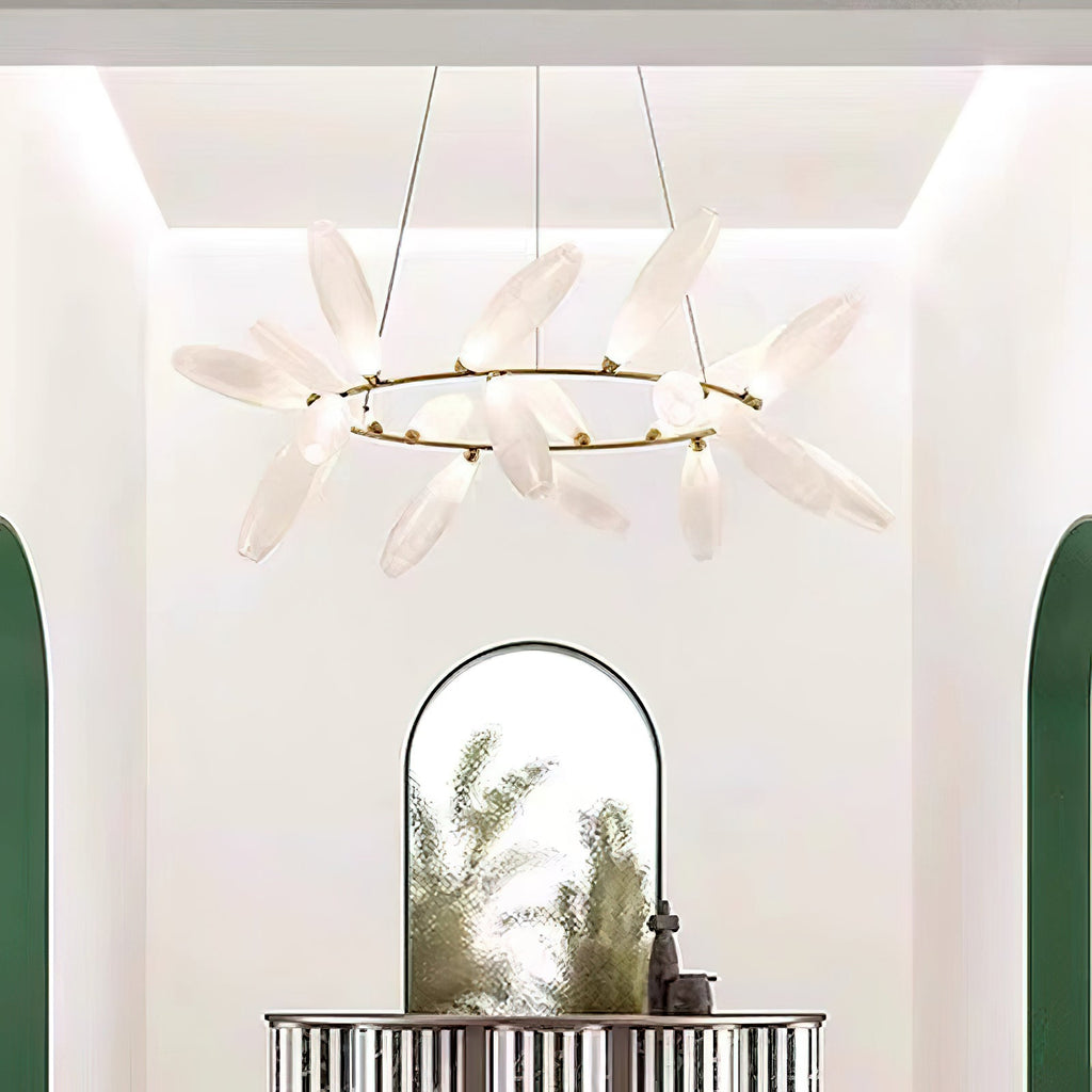 A round Clérachic chandelier of frosted white leaves on a gold ring hangs in a bright entrance with an arched mirror and a green-framed doorway.