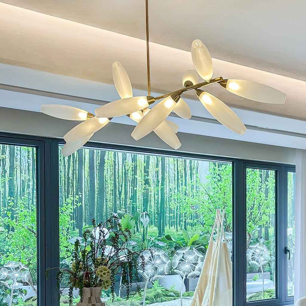 A Clérachic chandelier glows warm beneath a coved ceiling, its glass leaves branching on a gold rod in front of a window onto a garden of trees.