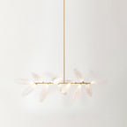 A linear Clérachic chandelier of frosted glass leaves hangs from a long gold rod against a pale backdrop, with a short cluster of leaves on each side.