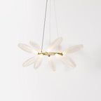 A round Clérachic chandelier seen from the side, its white glass leaves clustered around a thin gold ring on a pale backdrop.