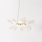 A round Clérachic chandelier in three-quarter view, with white glass leaves radiating from a gold ring on a pale backdrop.