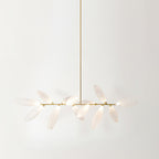 A long, linear Clérachic chandelier of frosted glass leaves on a gold bar, hung from a single gold rod against a pale backdrop.