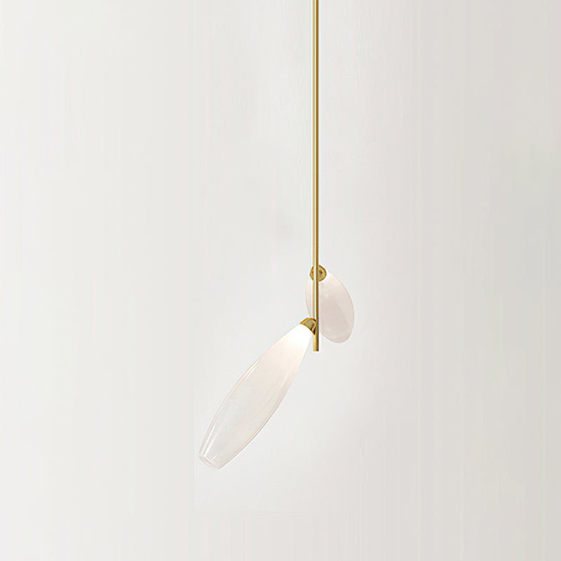 Close view of two frosted glass leaves on a gold stem, one angled down, from this Clérachic chandelier against a pale wall.