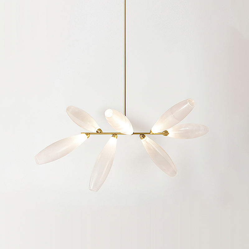 A short linear Clérachic chandelier of lit frosted glass leaves on a gold bar, hung from a gold rod against a pale wall.