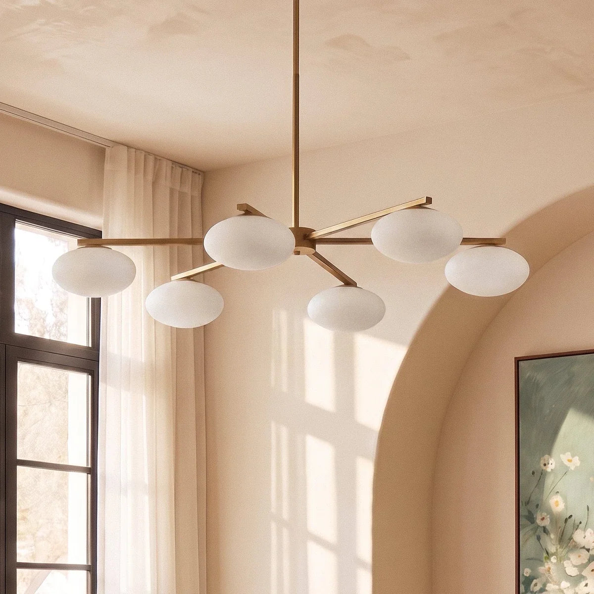 Clérachic six-head chandelier close-up with the shades unlit, frosted oval glass on slim brass arms in soft daylight.