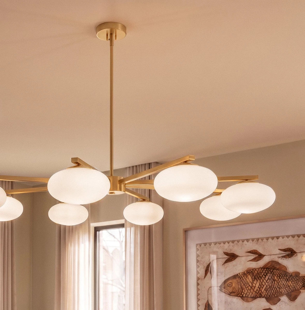 Close view of a Clérachic eight-head chandelier, showing the brass canopy, central stem and glowing opal glass shades.