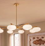Close view of a Clérachic eight-head chandelier, showing the brass canopy, central stem and glowing opal glass shades.