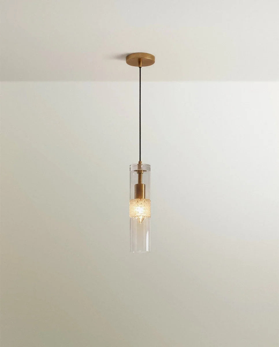 Clérachic slim pendant, a clear glass cylinder with a brass fitting and black cord hanging below a plain ceiling canopy.
