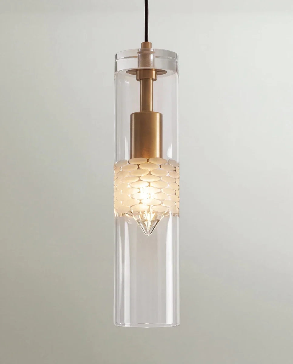 Clérachic pendant close-up, a clear glass cylinder around a brass holder and a frosted pebble-textured band, lit warm.
