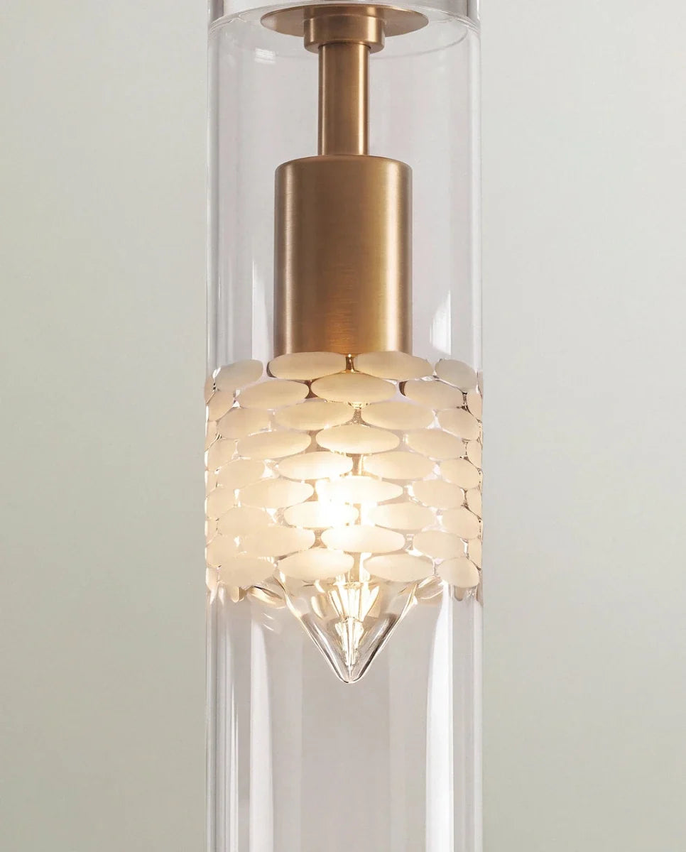 Clérachic pendant detail, brushed brass holder above a glowing frosted band with a pebble pattern in a clear cylinder.