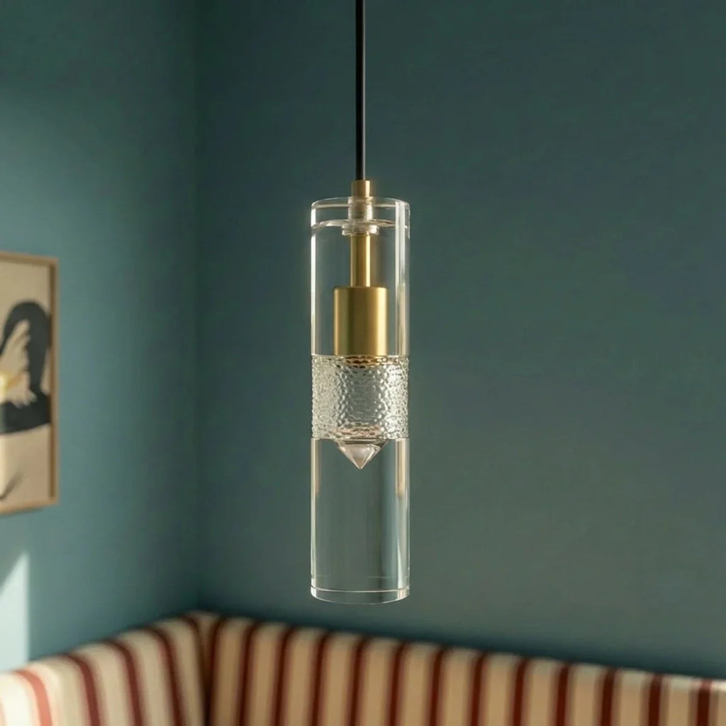 Clérachic clear glass cylinder pendant with brass fitting, close beside a teal wall and a striped banquette.