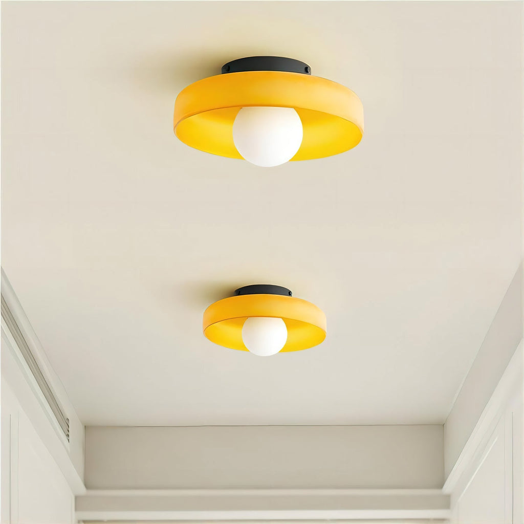 Two amber-orange glass-disc ceiling lights from Clérachic, each with a white globe and black plate, on a plain white ceiling.