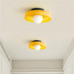 Two amber-orange glass-disc ceiling lights from Clérachic, each with a white globe and black plate, on a plain white ceiling.