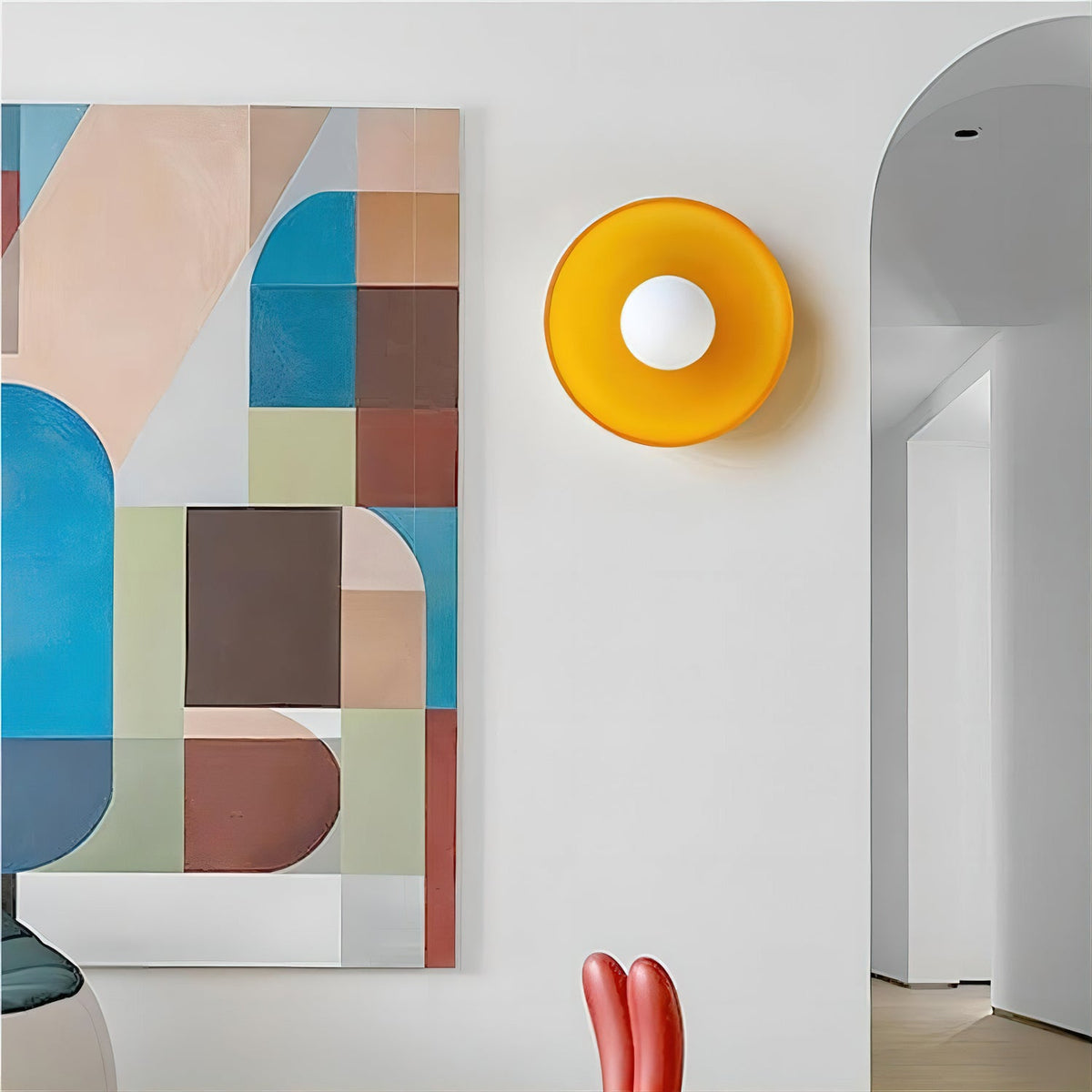 An amber glass-disc wall light from Clérachic with a white globe, mounted beside an arched doorway and a colourful geometric painting.