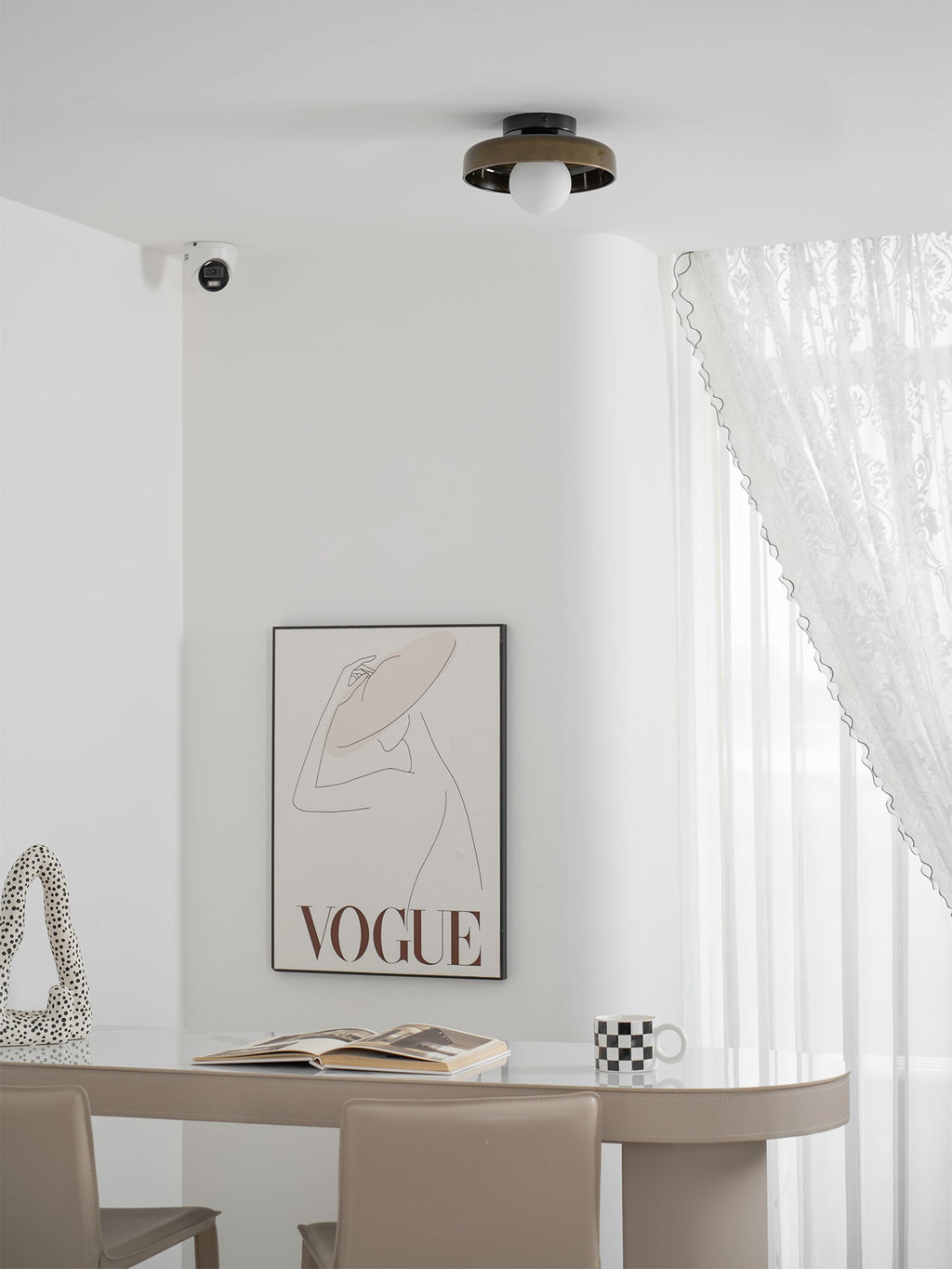 In a room with lace curtains and a framed fashion print, a Clérachic dark glass-disc light sits flush on the ceiling.