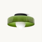 Green glass disc ceiling light from Clérachic with a black plate and a white globe bulb, shown on an off-white backdrop.