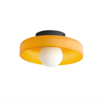 Amber-orange glass disc ceiling light from Clérachic, with the white globe sitting below the rim, on a plain white backdrop.